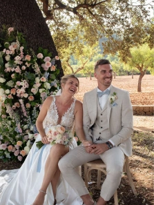 Brautpaar sitzt bei der freien Trauung vor Blumenbogen, Hochzeitszeremonie