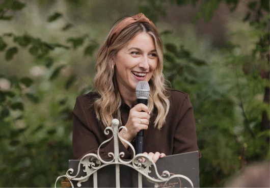 Sarah Paschke spricht als freie Traurednerin ins Mikrofon bei einer Hochzeit